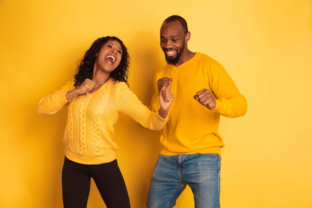 女孩年轻感性的非裔美国人 穿着黄色背景的明亮休闲服美丽的情侣人类情感的概念 面部表情 关系 广告跳舞和唱歌面部成人关系