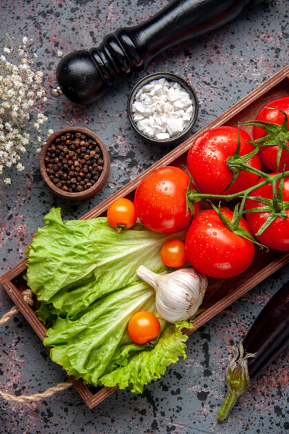 西红柿顶视图新鲜的红色西红柿配大蒜和绿色沙拉在蓝色表面的木板内食物午餐沙拉成熟的颜色餐生菜一餐木头