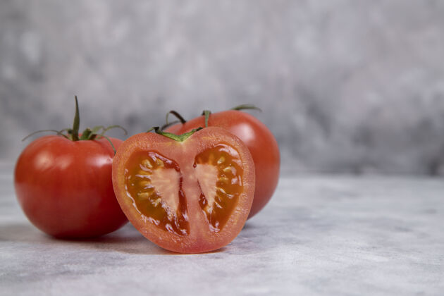 成熟整个和切片多汁的红色西红柿放在大理石上自然素食红色