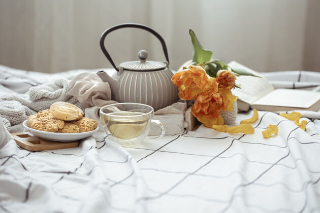 休息一天一杯茶 一个茶壶 一束郁金香和饼干躺在床上静物周末和春天的早晨的概念床早晨房子