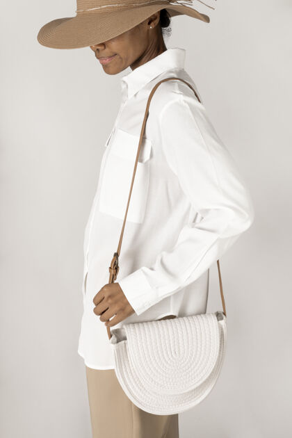 非洲裔美国人一个黑色的女人拿着一个白色的编织棉绳袋模型手提包时尚包
