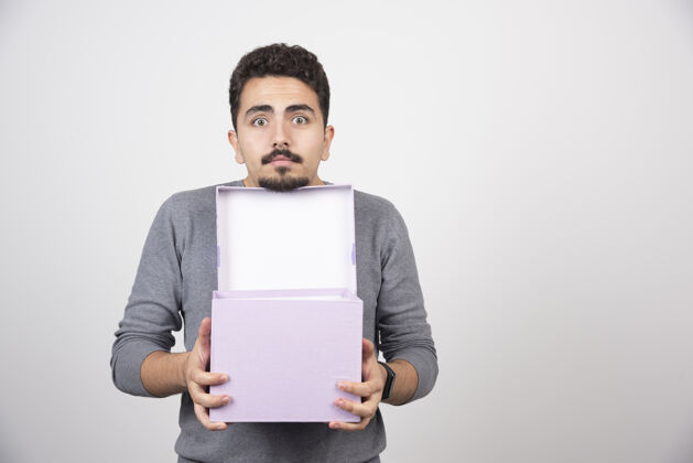 紫色一个年轻人拿着一个打开的紫色盒子盖在白墙上礼物男人盒子