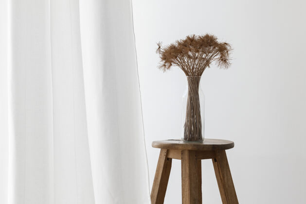 白色房间一束干纸莎草植物在一个玻璃花瓶里 放在一个白色窗帘旁的木凳上复制空间木凳子花瓶
