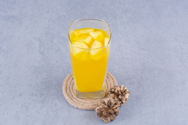 玻璃松果 一杯果汁和三脚架 放在大理石上可口松果美味