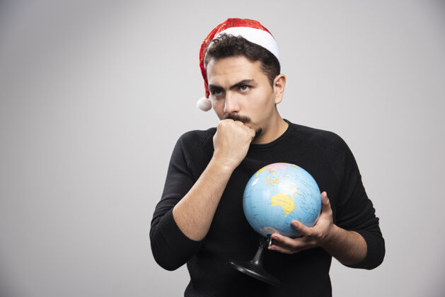 地理一个戴着圣诞老人帽子的愤怒的男人伸出拳头拿着地球仪时尚成人黑发