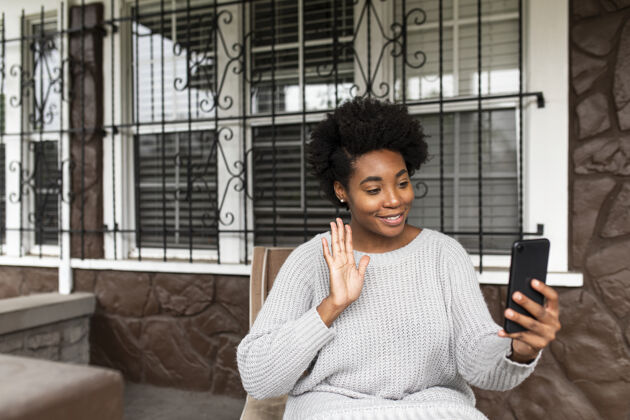 手机非洲裔美国女人在打视频电话互联网放松坐着