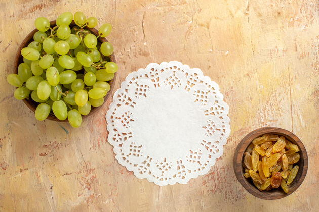 食物顶部特写查看葡萄碗葡萄干和绿色葡萄花边桌布上的桌子葡萄健康木材