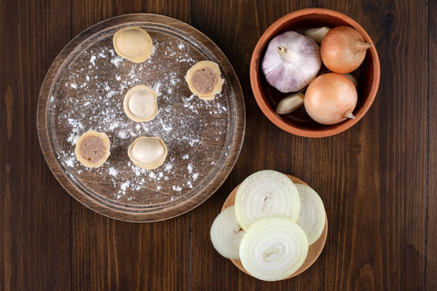 佩尔曼一块木板 上面放着自制的佩尔曼饺子和一碗洋葱木板洋葱蔬菜