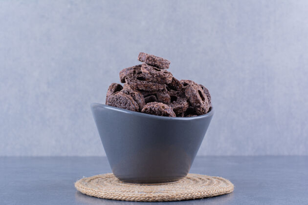 健康健康早餐 巧克力玉米圈放在石头上的黑碗里蛋白质小环燕麦