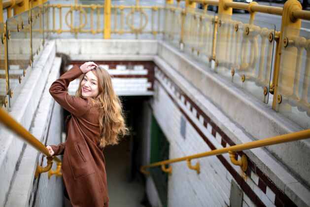 人年轻漂亮的金发女郎微笑着站在通往地下的楼梯上生活方式人物华丽