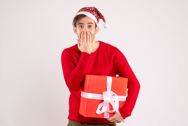 圣诞节前视图：一个戴着圣诞帽的年轻人在白色背景下捂着嘴白色微笑秘书