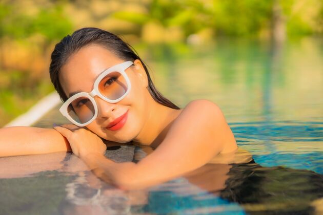 女人美丽的亚洲年轻女子在游泳池里放松的画像度假水快乐