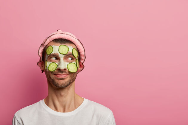皮肤护理脾气好的快乐男人戴着面膜和黄瓜 享受早上的spa程序 想看起来精神焕发应用阳刚面部护理