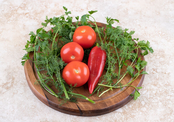 头顶在木板上的西红柿和胡椒与绿色的特写照片食物滴成熟