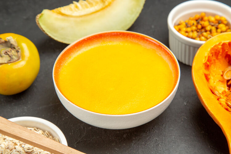 汤正面图美味的南瓜汤在盘子里放在一张深色的桌子上 盘子里有彩色的汤黑晚餐黄油