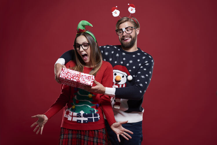 女人有趣的男人站在糖果手杖旁边送圣诞礼物微笑极客圣诞节