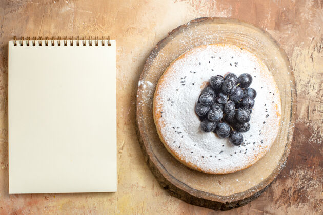 浆果蛋糕俯视图切菜板上的黑葡萄蛋糕白色笔记本黑色黑板顶部