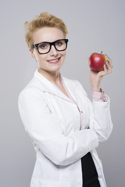 牙科健康年轻漂亮的医生手里拿着成熟的苹果手持人制服