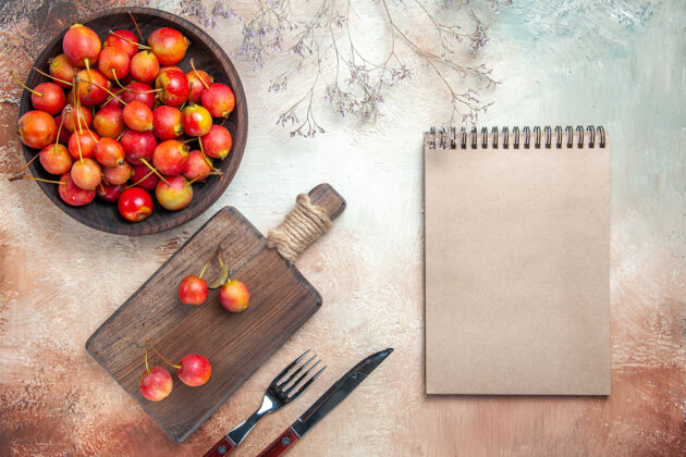 特写顶视图樱桃浆果上厨房板碗樱桃叉刀笔记本顶部板刀