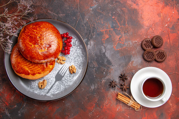 碗俯瞰美味的馅饼和一杯茶在黑暗的地板上甜甜的糕点馅饼热的派地板