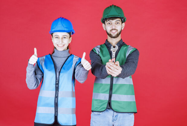 装备男 女工程师 戴头盔 手持金属扳手 并显示积极的手势成人工人满意