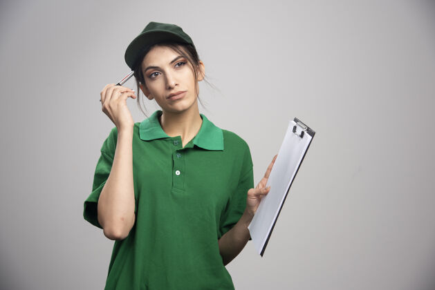 帽子穿着绿色制服拿着剪贴板的女送货员剪贴板送货女人