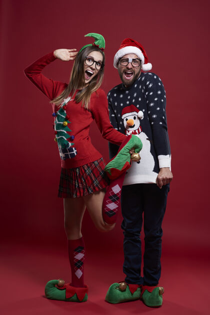 女人穿着滑稽圣诞服装的年轻夫妇邦德圣诞帽尖叫