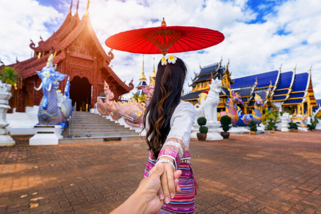 亚洲女人牵着男人的手 把他带到清迈的寺庙旅游清迈雨伞