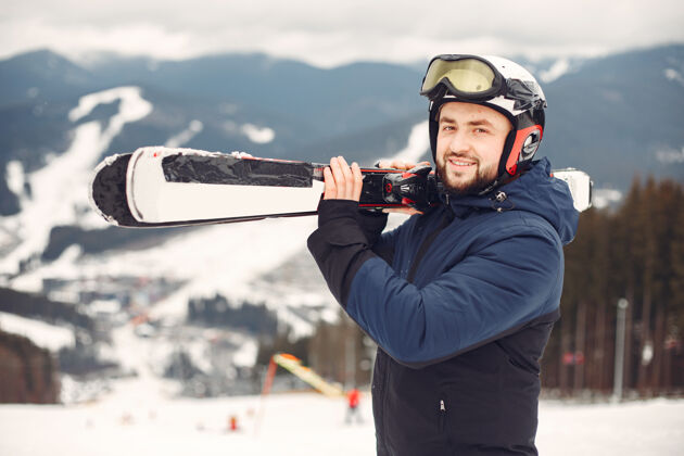 成人穿着滑雪板套装的人手拿滑雪板的山上的运动员在地平线上关于运动的概念年轻蓝色下雪