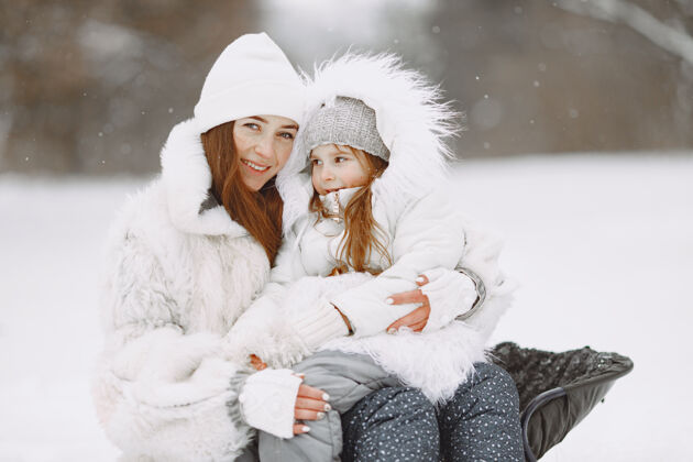 羊毛一家人在一起过圣诞节一个公园里的女人和小女孩带着雪橇的人自然雪运动
