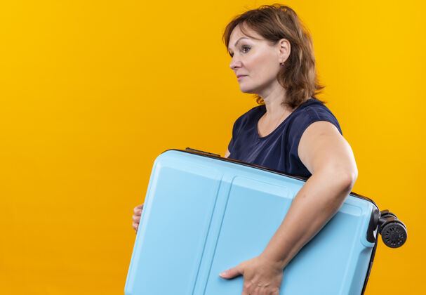 壁板看着身边的中年旅行家女子提着手提箱孤零零的黄色背景中年人手提箱旅客