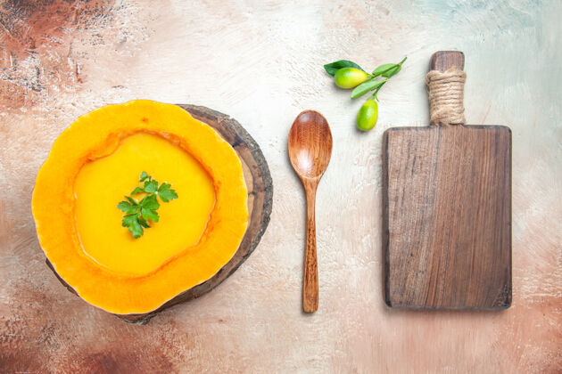 勺子从远处俯视一个汤勺南瓜汤在菜板旁边的勺子砧板上食物蔬菜胡桃南瓜