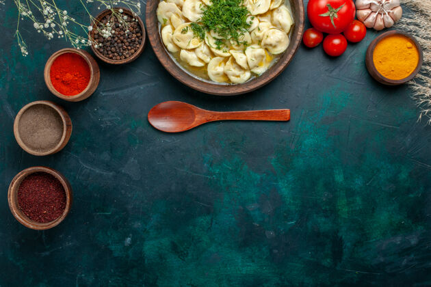 生的俯瞰美味的饺子汤与不同的调味料上一个深绿色的背景肉汤蔬菜食品面团面团景观餐