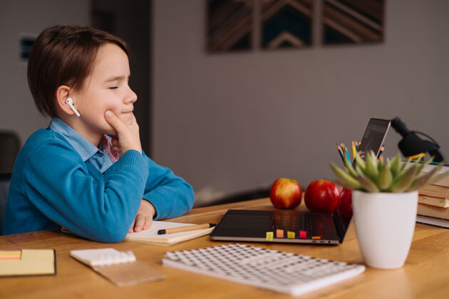 通话一个未成年男孩用笔记本电脑在线上课笔记本电脑课程耳机
