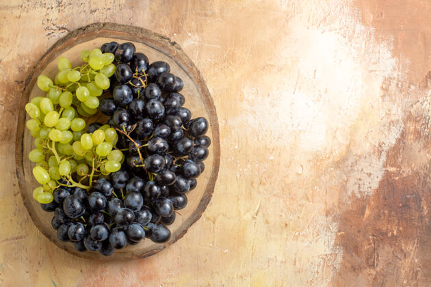 浆果顶视图葡萄绿色和黑色的葡萄串在木制砧板上收获有机葡萄酒
