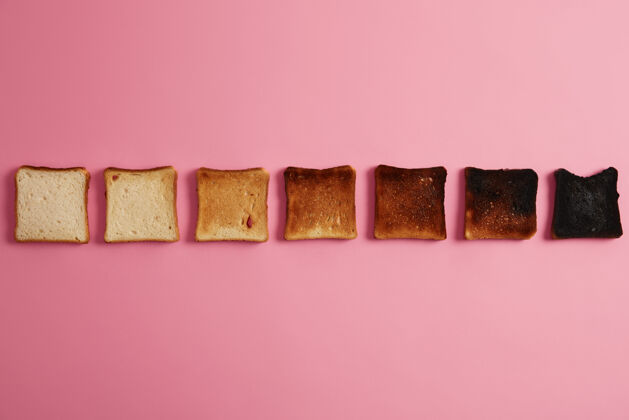 碳水化合物在烤的不同阶段的面包片松脆的烤面包片排成一排在粉红色背景上最后一片完全烧焦正在烤面包从未烤到烧焦俯视图背景头顶烧伤