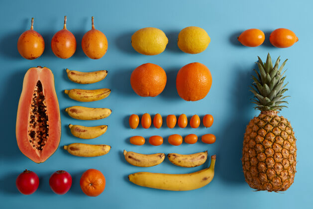 橙色在蓝色背景下收获多汁的热带异国水果木瓜 柠檬 香蕉 菠萝 金橘 柽柳制作冰沙的原料健康的素食有机食品水果颜色柑橘
