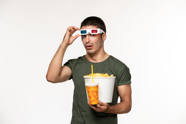 杯子正面图身穿绿色t恤的年轻男性手持土豆cips苏打水in-d太阳镜在白色墙上拍摄男性孤独电影电影成人电影