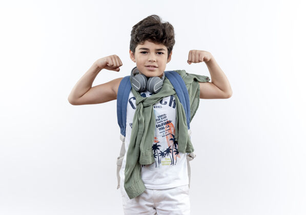 小高兴的小男生戴着背包和耳机做着强烈的手势隔离在白色背景上包小学生请戴上