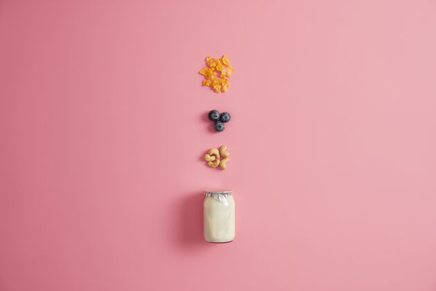有机一罐新鲜酸奶 谷类食品 蓝莓和腰果 用于早餐时准备美味的粥自制甜食或甜点的配料零食和节食概念粉色背景饮食膳食乳制品