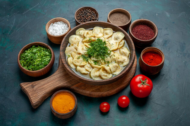 盘子俯瞰美味的饺子汤与不同的调味料在一个绿色的桌子上食物肉蔬菜面团汤饺子面团顶