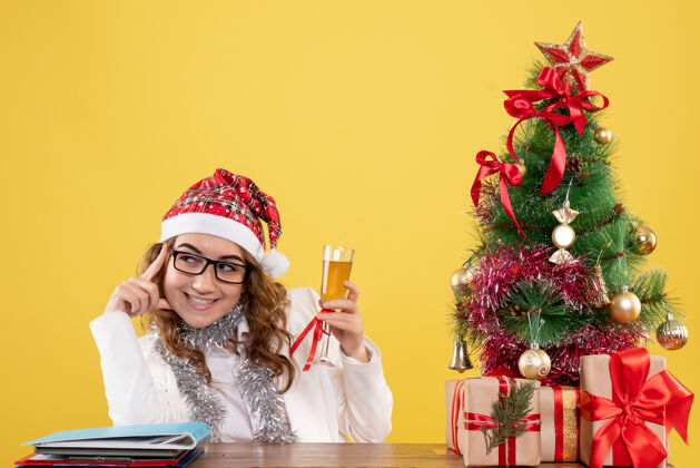 圣诞树前视图女医生用香槟庆祝圣诞节香槟人圣诞