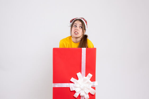 笔记本大圣诞礼物后面站着一个戴圣诞帽的女孩微笑圣诞老人生日