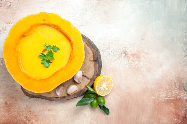 柑橘顶视图柠檬汤旁边的南瓜汤与香草大蒜板上南瓜南瓜草药
