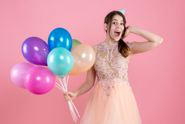 肖像前视图兴奋的女孩与党帽举行气球举行礼服公主