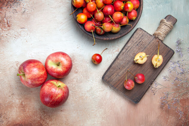 食物顶部特写查看樱桃树枝樱桃在碗里和板上三个苹果水果新鲜碗