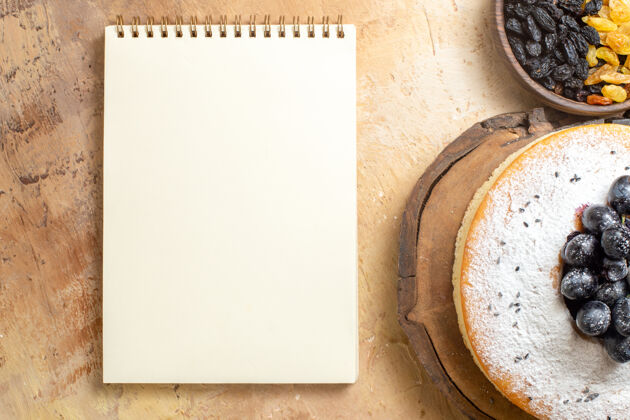 蛋糕顶部特写查看葡萄干一碗葡萄干蛋糕上的葡萄板白色笔记本垃圾年份纸
