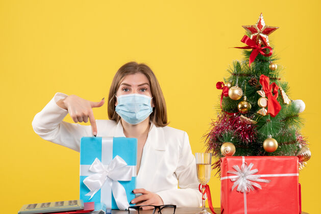 漂亮正面图：戴着无菌口罩的女医生带着礼物成人病毒大流行