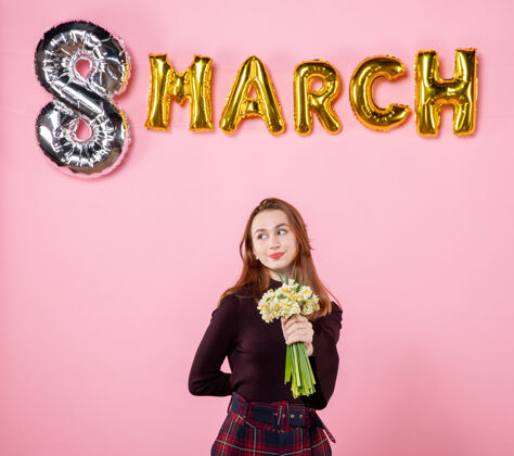 人正面图：手拿鲜花的年轻女性 粉色背景上的三月装饰派对妇女节三月激情平等性感礼物8日三月