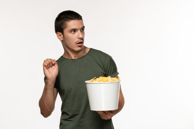景观正面图穿着绿色t恤的年轻男性 带着土豆 在浅白的墙上看电影 电影人 男性 孤独的电影 电影院电影院浅白色杯子